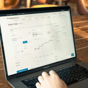 person using macbook pro on brown wooden table